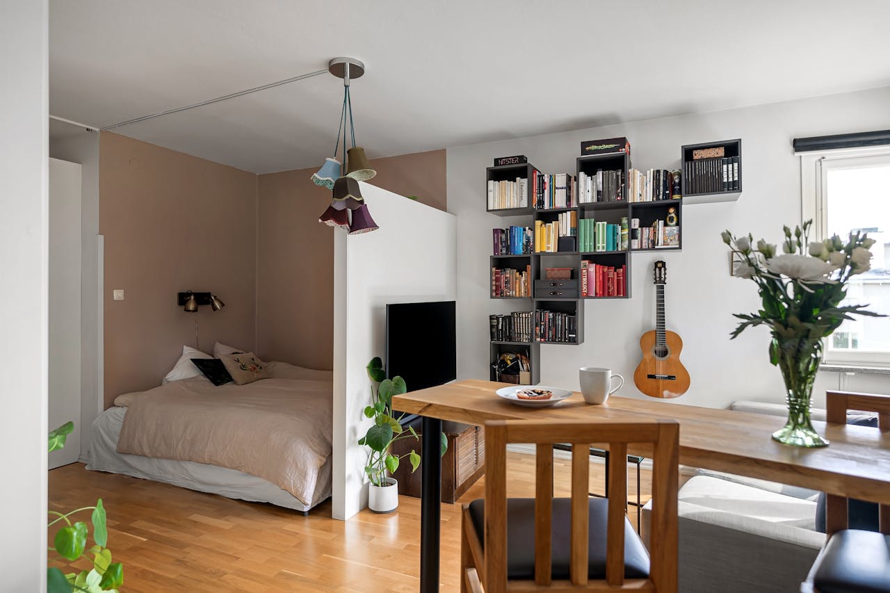 hero-img A stylish studio apartment with a cozy bed, bookshelf, and modern decor.
